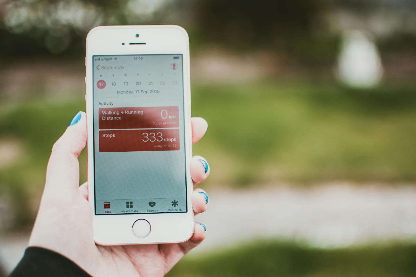 Hand holding an iPhone displaying a health and fitness app outdoors