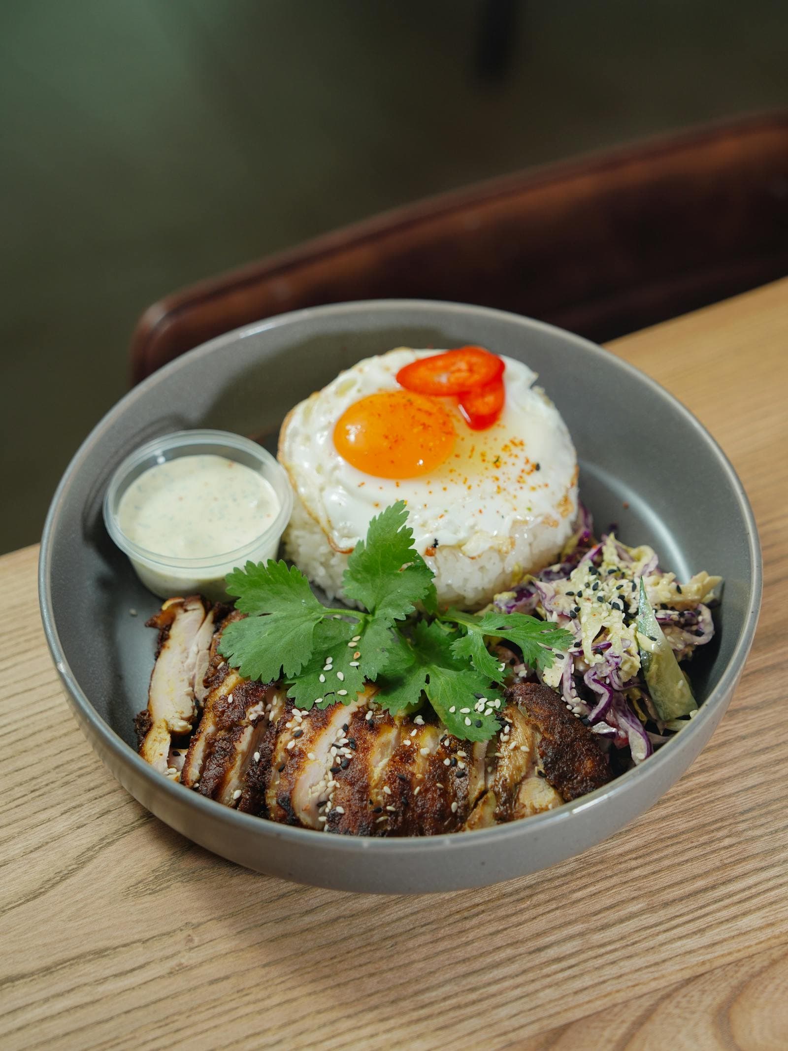 A meal-prep chicken and rice bowl with vegetables and fresh herbs