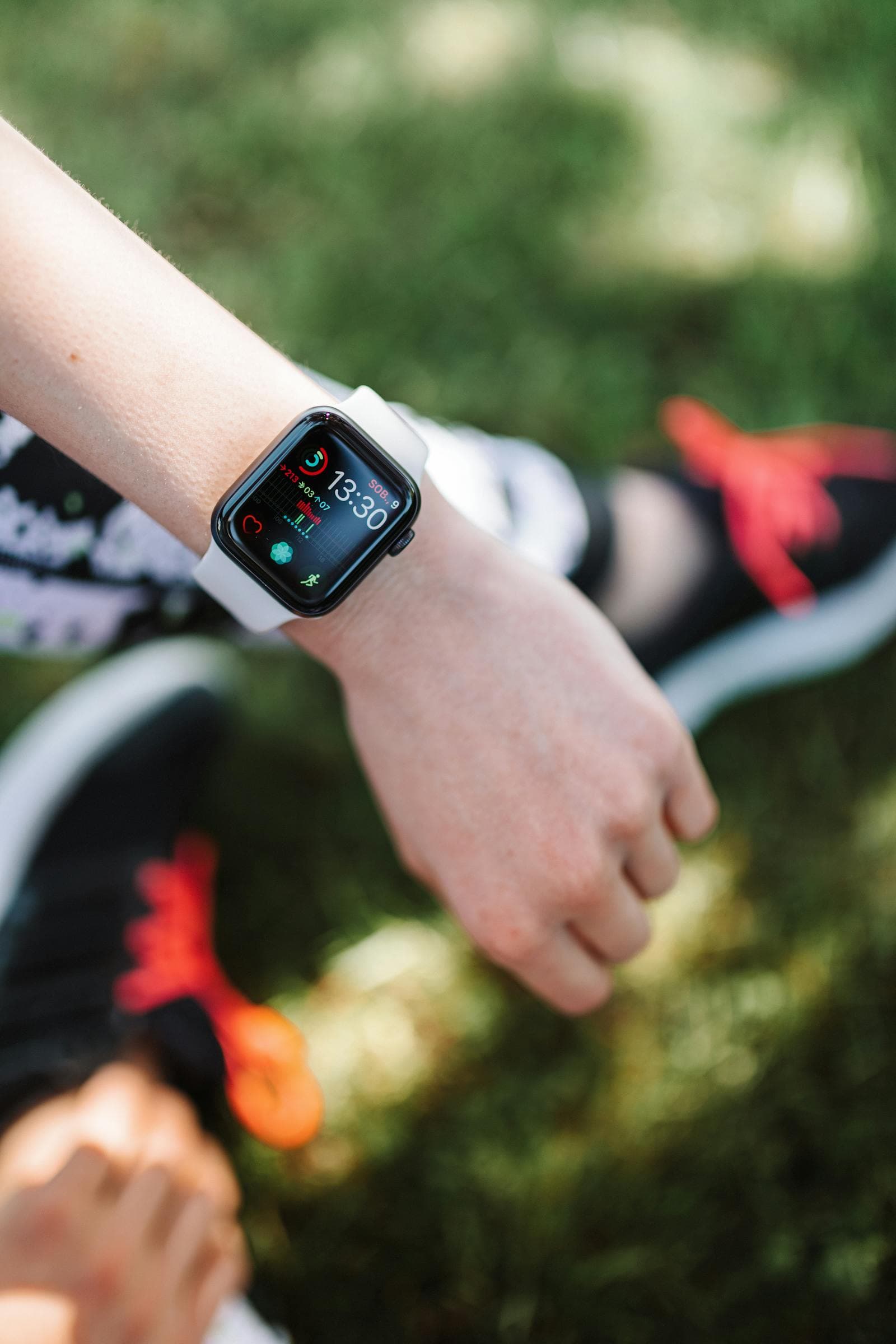 An Apple Watch on a wrist outdoors with sporty shoes visible — fitness tracking in context